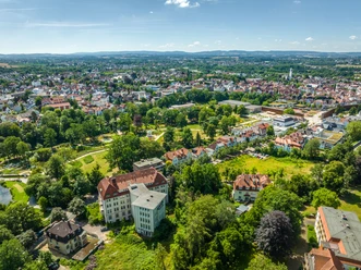 Luftaufnahme des Kurparks Bad Salzuflen: grüne Oase mit Gehwegen und historischen Gebäuden umgeben.