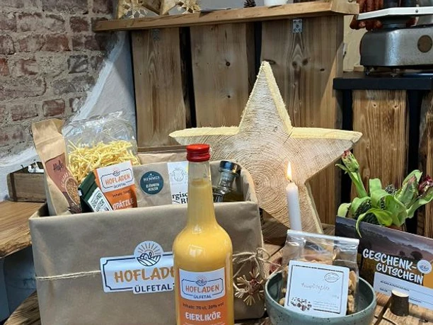 Hofladen Ülfetal Ein rustikaler Hofladen präsentiert regionale Produkte wie Eierlikör, Nudeln und Kerzen, umgeben von Holzdeko.