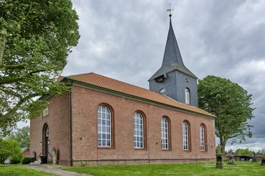 St. Andreas Kirche Cadenberge-Geversdorf Historische St. Andreas Kirche aus rotem Backstein mit hohem Turm und Rundbogenfenstern im Grünen.