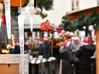 Weihnachtsmarkt feeling Verschneiter Weihnachtsmarkt mit geschmückten Ständen, Lichterketten und Menschen in Winterkleidung.</p>Snowy Christmas market with decorated stalls, fairy lights and people in winter clothing</p>.