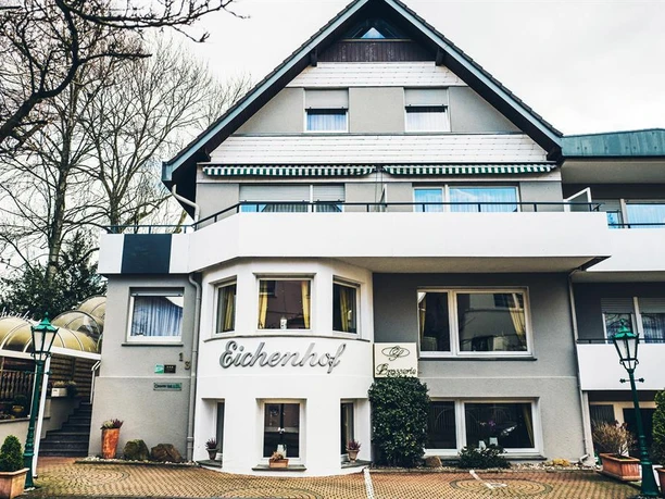 Antikhotel Eichenhof mit heller Fassade, Balkonen und gepflastertem Vorplatz