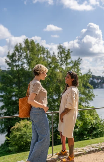 Zwei Frauen stehen am Ufer des Domsees in Ratzeburg und genießen das sommerliche Wetter.