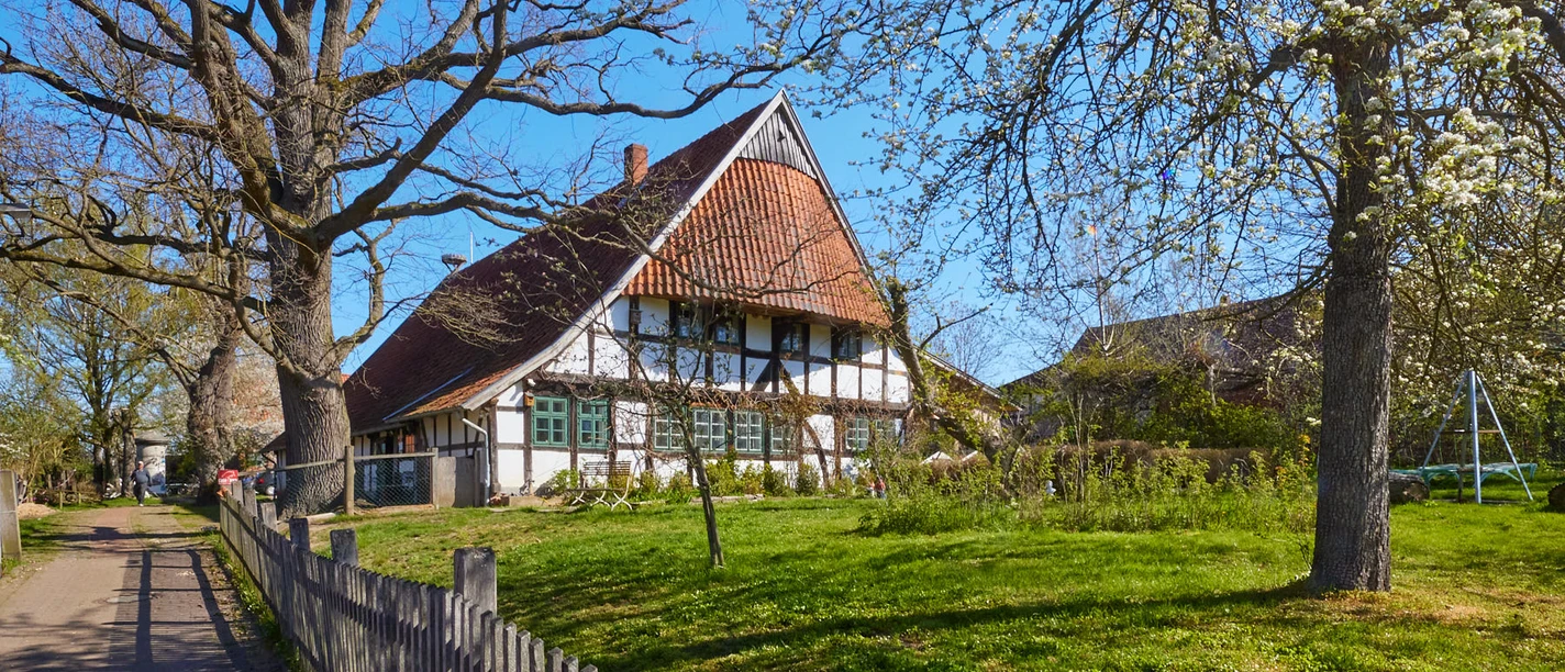 Windheim No2 | Historische Hofstelle mit Café und Storchenmuseum Fachwerkhof mit Strohdach, Grünfläche, blühende Bäume; Nutzung als Café und Storchenmuseum in Petershagen.