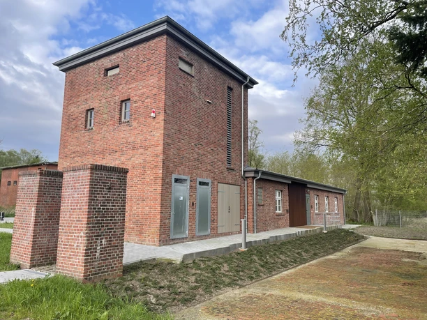 Backsteingebäude des Erinnerungsorts Lager XII Dalum mit barrierefreiem Zugang und umgebenden Bäumen