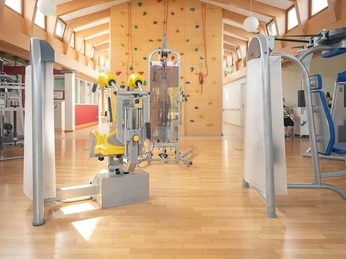 Bad Driburg_Gräfliche Kliniken_Caspar Heinrich Klinik_169.jpg Heller Trainingsraum mit modernen Fitnessgeräten und Kletterwand unter einem Holzgebälk.