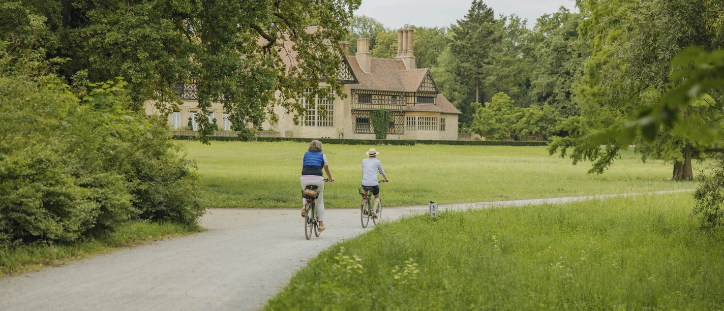 Schloss Cecilienhof im Neuen Garten Radfahrende im Neuen Garten am Schloss Cecilienhof im Sommer