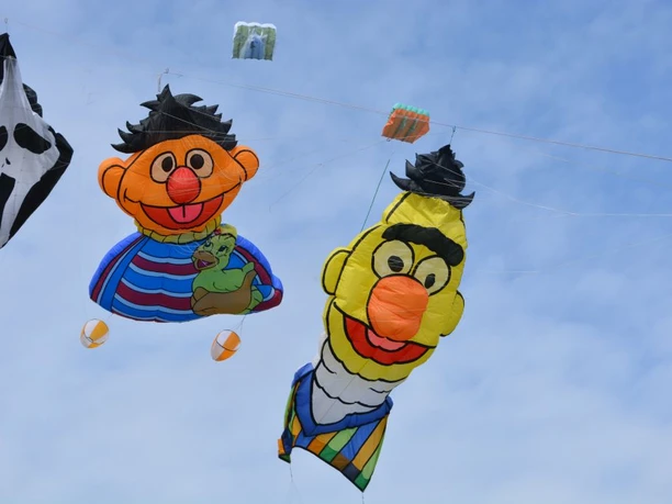 Drachenfest in Geeste am Speichersee.jpg Bunte Drachen in Form bekannter Figuren schweben beim Drachenfest über dem Speichersee Geeste.