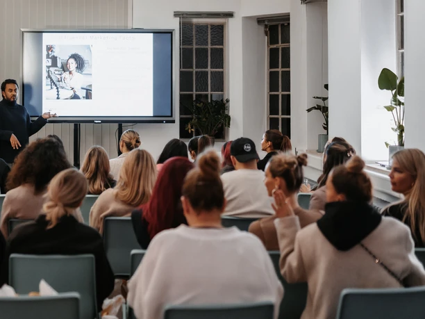 BACKYARD LOFT - Tagung Seminar room with speaker in front of audience and presentation on screen.