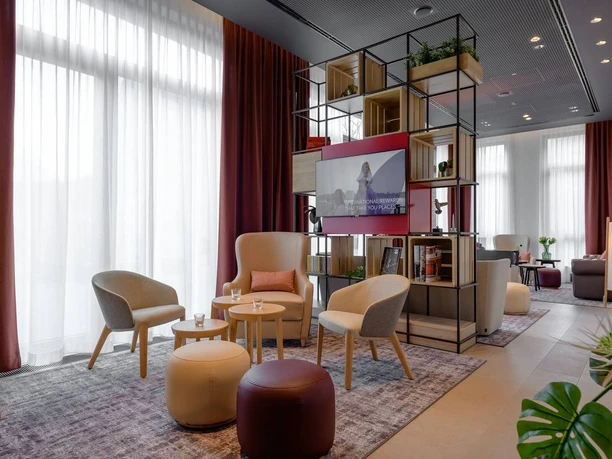 Moderner Loungebereich mit stilvollen Sesseln, dezenten Farben und großen Fenstern für viel Licht.