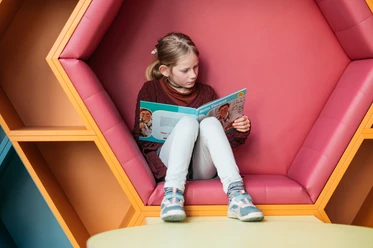 Mädchen mit blonden Haaren liest ein Buch