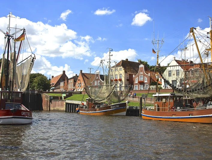 Hafen von Greetsiel Kutter, Wasser, Gebäude, historische Häuserzeile, blauer Himmel