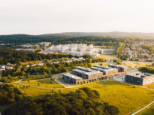 Luftaufnahme eines modernen Campus in grüner Umgebung, mit weitläufigen Wiesen und Gebäudekomplex.
