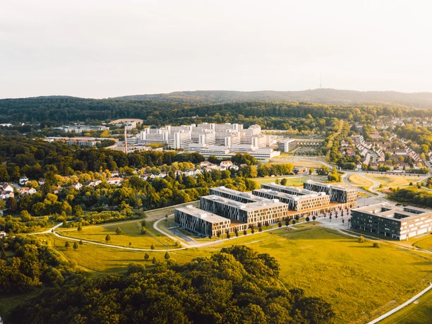 Luftaufnahme eines modernen Campus in grüner Umgebung, mit weitläufigen Wiesen und Gebäudekomplex.