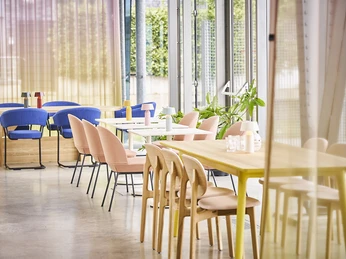 DSC06713.jpg Lichtdurchfluteter Raum mit bodentiefen Fenstern und drei Gruppentischen mit bunten StühlenLight-flooded room with floor-to-ceiling windows and three group tables with colorful chairs