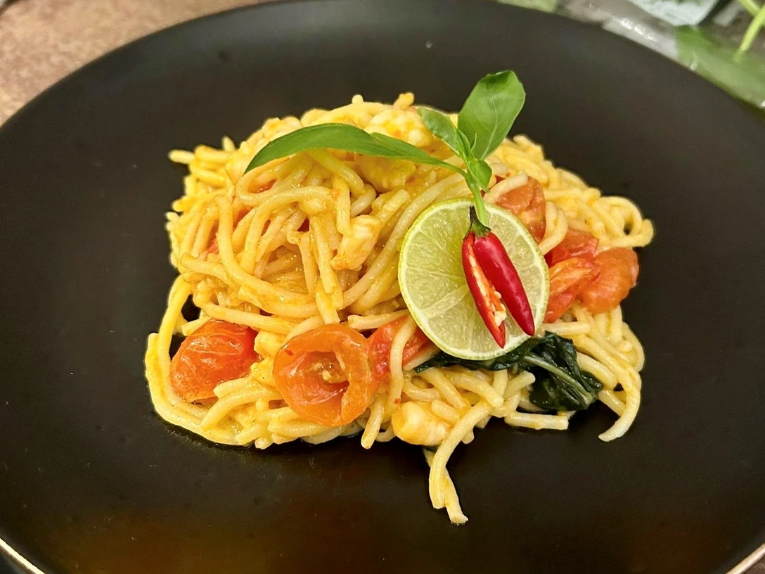 Pasta_CC-BY-SA_Teutoburger_Wald_Stadt_Schloss_Holte-Stukenbrock.jpg Spaghetti auf schwarzem Teller, garniert mit Tomaten, Limettenscheiben, Chili und einem frischen Basilikumblatt.