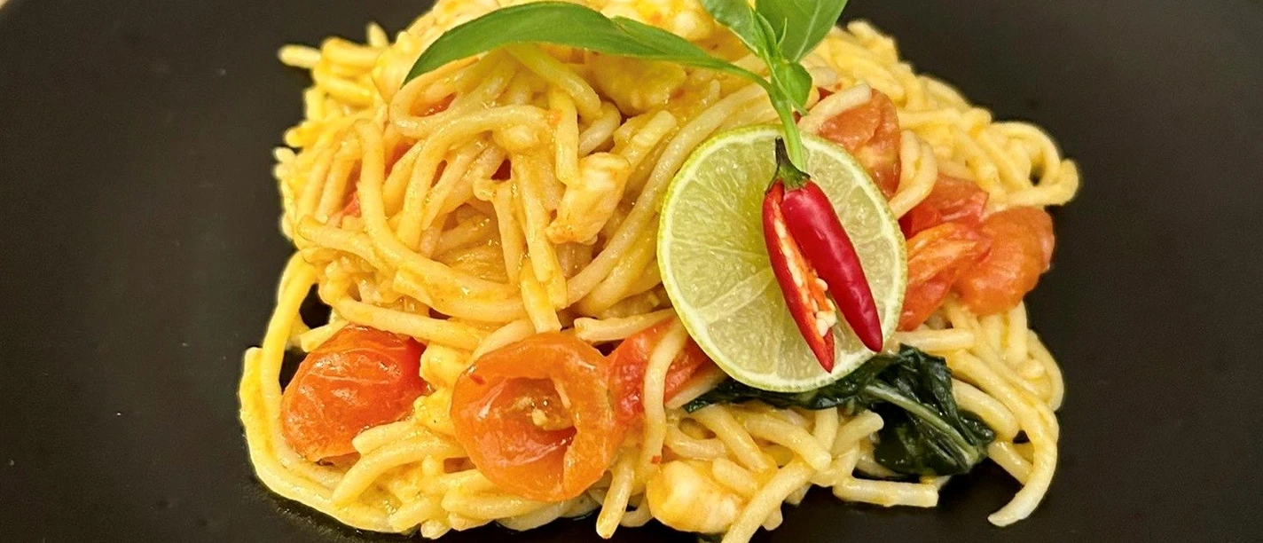 Pasta_CC-BY-SA_Teutoburger_Wald_Stadt_Schloss_Holte-Stukenbrock.jpg Spaghetti auf schwarzem Teller, garniert mit Tomaten, Limettenscheiben, Chili und einem frischen Basilikumblatt.