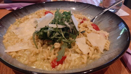 Bärlauch_Spirelli_CC_BY_SA_Teutoburger_Wald_Stadt_Schloss_Holte-Stukenbrock.jpg Pasta mit Bärlauch-Soße, Tomaten und Rucola, garniert mit Parmesan auf einem grünen Teller.