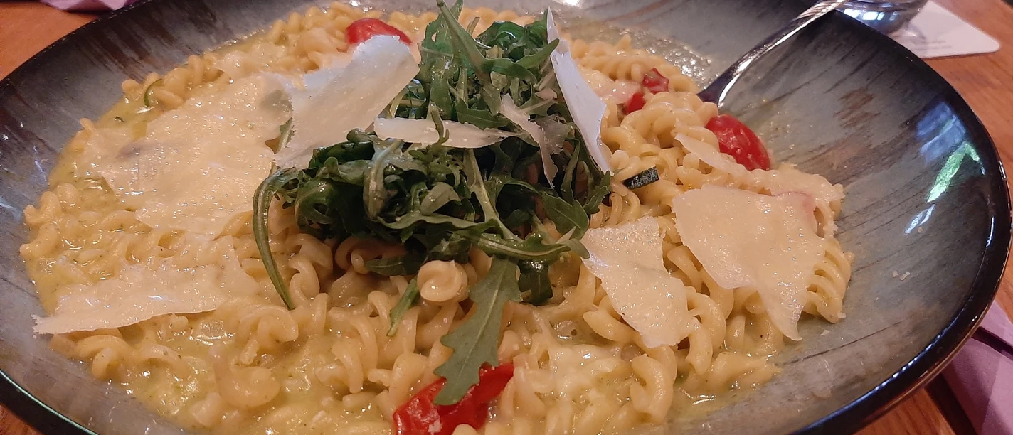 Bärlauch_Spirelli_CC_BY_SA_Teutoburger_Wald_Stadt_Schloss_Holte-Stukenbrock.jpg Pasta mit Bärlauch-Soße, Tomaten und Rucola, garniert mit Parmesan auf einem grünen Teller.
