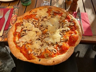 Pizza_Funghi_CC_BY_SA_Teutoburger_Wald_Stadt_Schloss_Holte-Stukenbrock.jpg Pizza mit reichlich Tomatensoße, frischen Champignons und großzügigen Käsestreifen auf knusprigem Boden.