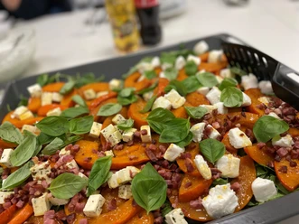 Kürbispizza_CC-BY-SA_Teutoburger_Wald_Stadt_Schloß_Holte-Stukenbrock.jpg Ofenfrische Pizza mit Kürbisscheiben, Feta, Baconwürfeln und Basilikumblättern auf dem Tisch.