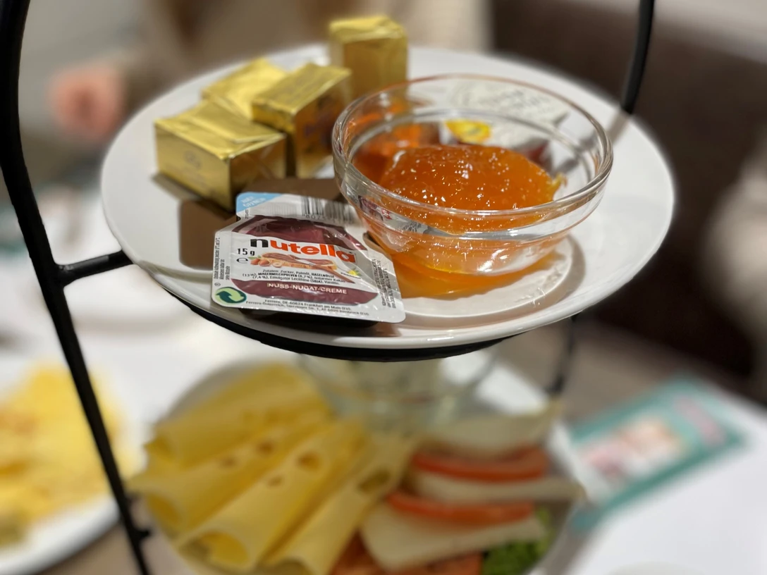 Frühstücks_Etagere_CC_BY_SA_Teutoburger_Wald_Stadt_Schloss_Holte-Stukenbrock.jpg Eine Etagere mit Käse, Gebäck, Marmelade und Nutella, arrangiert für ein Frühstück.