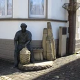 Korbmacher-Museum Dalhausen Eine Korbmacherstatue aus Bronze vor dem Museum, mit geflochtenen Körben und typischen Arbeitsgeräten.