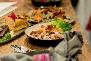 Tigermilch The image depicts inviting plates with creatively presented, fresh dishes featuring colorful ingredients, set on a wooden table under warm lighting.