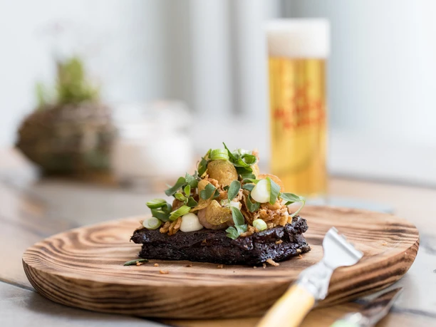 NeoBiota An artfully arranged gourmet dish with fresh herbs and a delicious drink in the background.