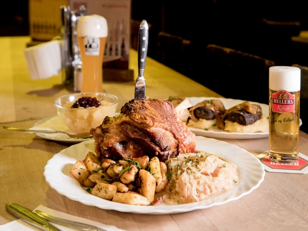 Hellers Brauhaus Ein gedeckter Tisch mit verschiedenen deftig mächtigen Speisen und ein Glas Kölsch-