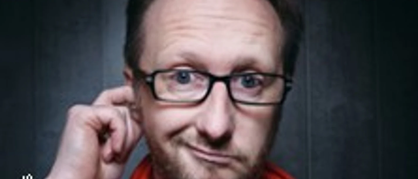 Mann mit Brille und skeptischem Blick vor dunklem Hintergrund mit auffälligem Titeltext.
