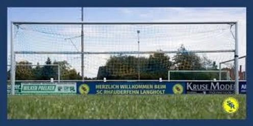 Sportanlage_SC Rhauderfehn_ Langholt Fußballtor mit Netz auf einem Spielfeld, Werbebanner mit Text 'Herzlich Willkommen beim SC Rhuderfehn Langholt' und Firmenlogos im Hintergrund.