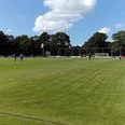 Sportplatz_an_der_Grundschule_Collinghorst Fußballfeld mit Spielern, umgeben von Bäumen unter einem leicht bewolkten Himmel.