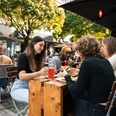 Freddy Schilling Eigelstein Junge Mensch essen Burger an einem Holztisch in der Außengastronomie.Young people eating burgers at a wooden table in an outdoor restaurant.