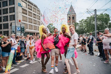 A colorful and cheerful parade scene at Cologne Pride with an exuberant atmosphere, music and confetti.