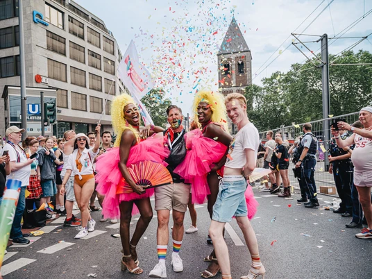 Eine bunte und fröhliche Parade-Szene beim Cologne Pride mit ausgelassener Stimmung, Musik und Konfetti.A colorful and cheerful parade scene at Cologne Pride with an exuberant atmosphere, music and confetti.
