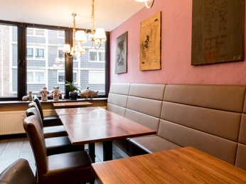 Restaurant Great Wall Innenansicht vom Restaurant mit asiatischen kleine Dekorationen, abstrakte Malerei an den roten Wänden und Sitzgarnitur aus Leder.Interior view of the restaurant with Asian-inspired decorations, abstract paintings on the red walls and leather seating.