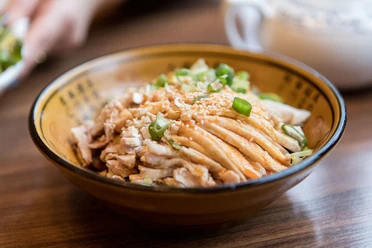 Restaurant Great Wall Close-up of a small porcelain bowl filled with cooked pork and spring onions.