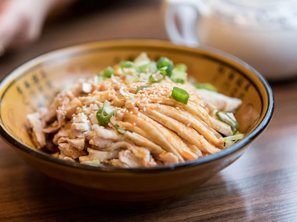 Restaurant Great Wall Close-up of a small porcelain bowl filled with cooked pork and spring onions.