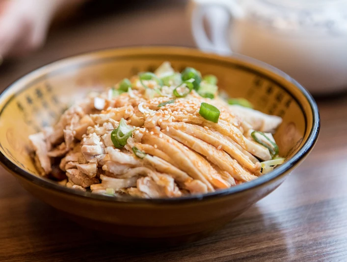 Restaurant Great Wall Nahaufnahme einer kleinen Porzellan Schüssel gefüllt mit gegartem Schweinefleisch und Frühlingszwiebeln.Close-up of a small porcelain bowl filled with cooked pork and spring onions.