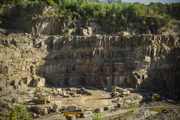 Steinbruch Ein Steinbruch in Lindlar mit schweren Baumaschinen vor steilen Felswänden und bewaldeten Höhen.