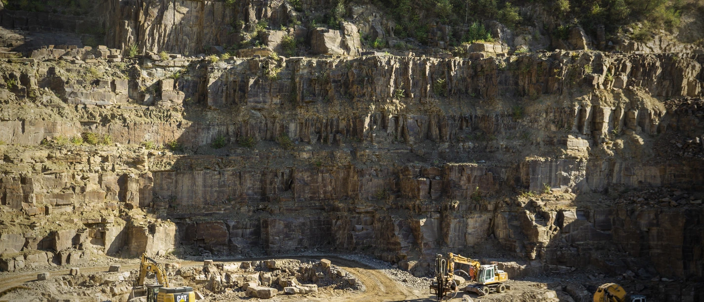 Steinbruch Ein Steinbruch in Lindlar mit schweren Baumaschinen vor steilen Felswänden und bewaldeten Höhen.