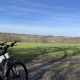 Radfahren in Nümbrecht Zwei Fahrräder stehen am Wegesrand vor einer weiten, grünen Landschaft mit blauen Himmel.