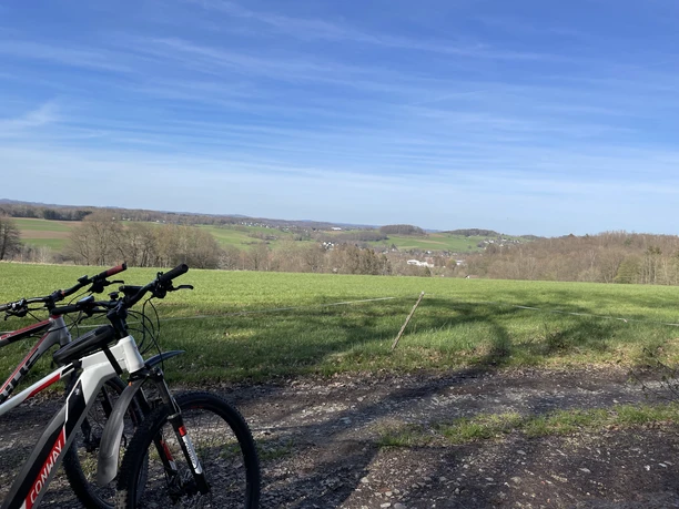 Radfahren in Nümbrecht Zwei Fahrräder stehen am Wegesrand vor einer weiten, grünen Landschaft mit blauen Himmel.