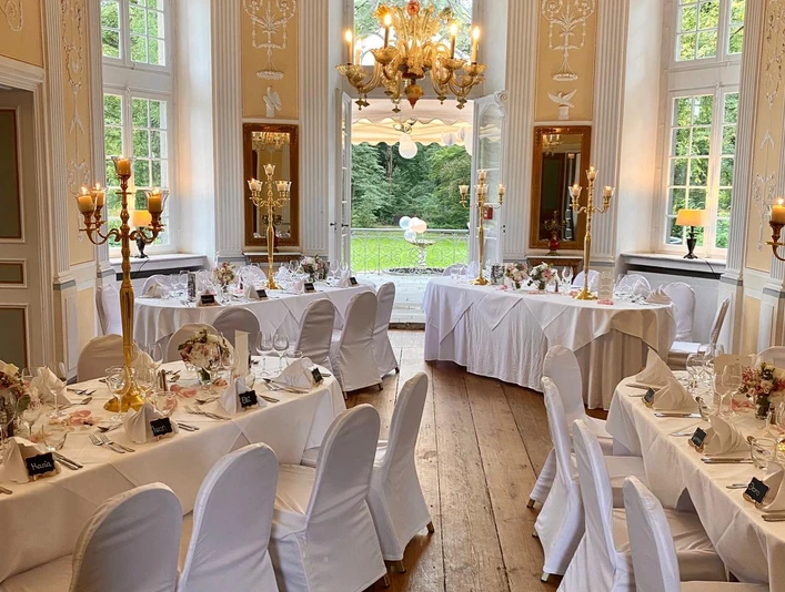 97d28a5d-915c-41d6-b024-fc9b7e3a686b.jpg Kleiner Raum im Barockstil mit weiß eingedeckten und festlich dekorierten TischreihenSmall room in Baroque style with rows of tables covered in white and festively decorated