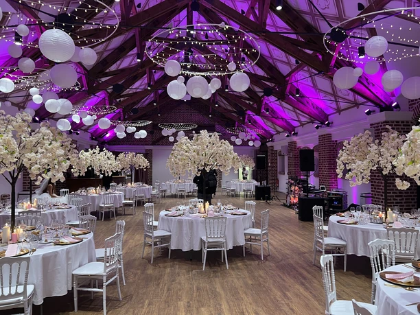 Eventscheune HZ Deko Baum.jpg Eventscheune mit Lichterkette und weißen Luftballons an der Decke und festlich dekorierten Banketttischen