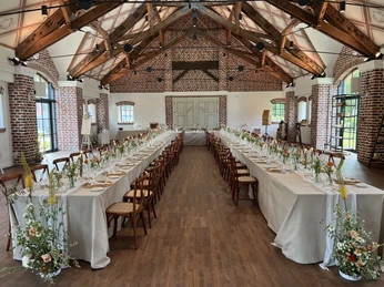 IMG_0577.jpg Stilvolle Eventscheune mit großen Fenstern, langen, gedeckten Tischreihen und BlumendekoStylish event barn with large windows, long, covered rows of tables and flowers