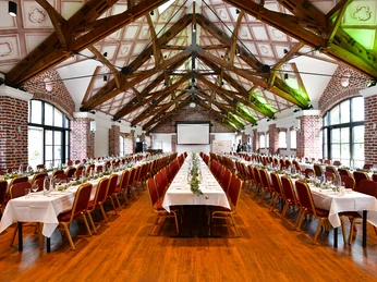 LO9_7098+Kopie++Laurence+Chataigne+Photography+2022.jpg Eventscheune mit großen Fenstern, langen, gedeckten Tischreihen und einer LeinwandEvent barn with large windows, long, laid tables and a screen