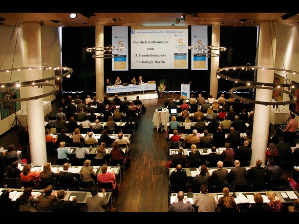 Produktive Arbeitsatmosphäre Ein gefüllter Kongresssaal beim 5. Bundekongress für Pathologie: Menschen sitzen in parlamentarischer Bestuhlung und folgen der Talksituation auf der Bühne