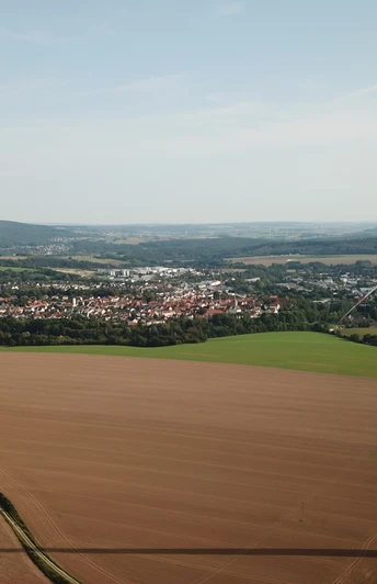 Blick über eine weitläufige, ländliche Landschaft mit einem markanten Windrad im Vordergrund.