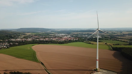 Blomberger_Spazierweg_Hohes_Feld_BM.JPG Blick über eine weitläufige, ländliche Landschaft mit einem markanten Windrad im Vordergrund.